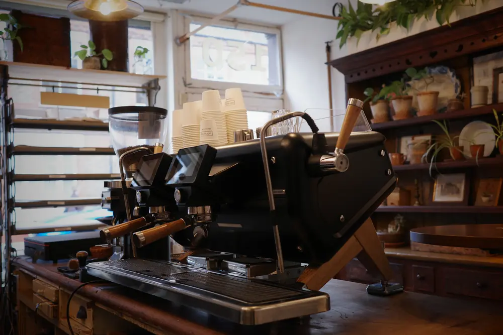 Espresso machine and grinders on the counter, shelves of crockery behind