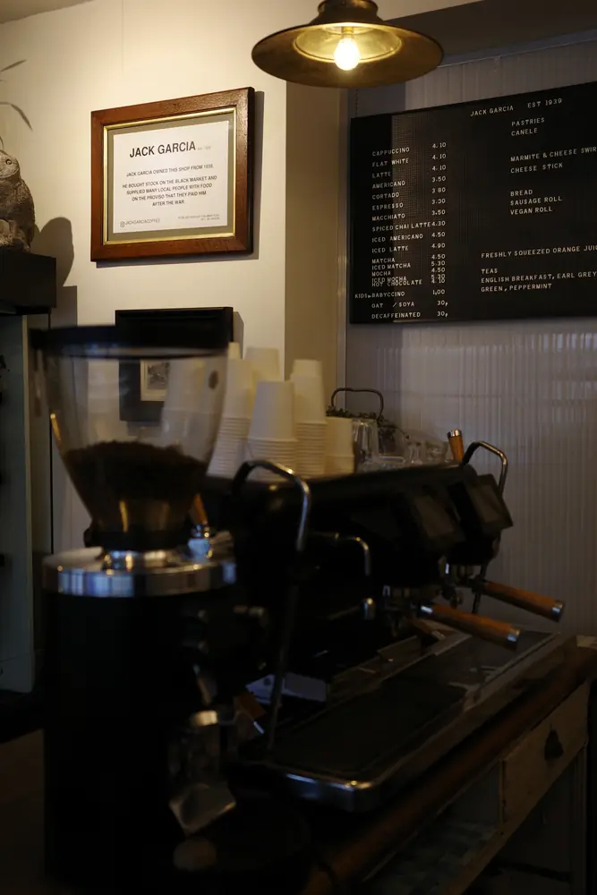 Espresso machine under a brass pendant lamp beside the menu board
