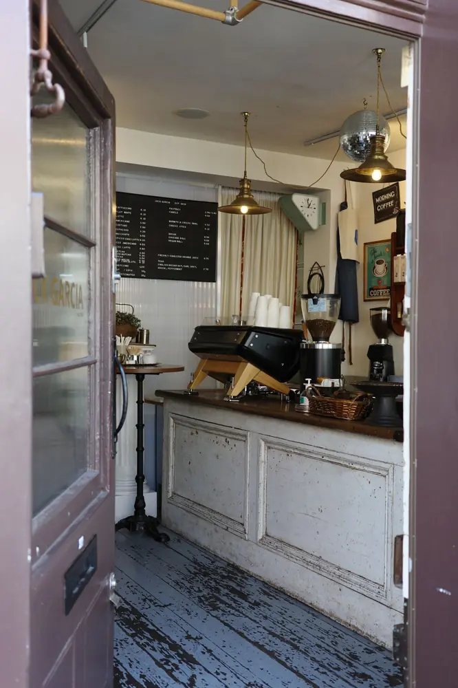 View through the open front door to the counter, espresso machine and menu board